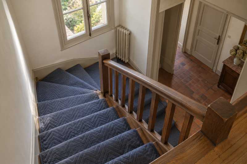 Couverture de protection déroulée sur les marches d'un escalier à quart tournant