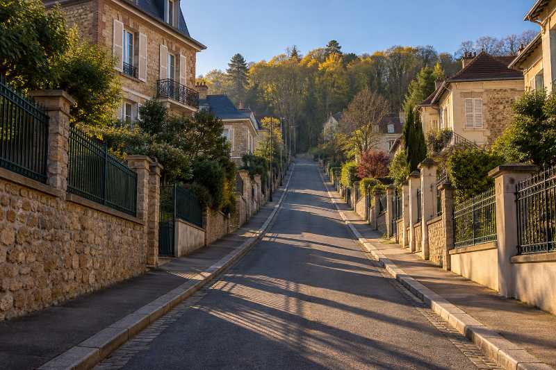Rue en forte pente déserte à l'aube, longues ombres portées sur la chaussée