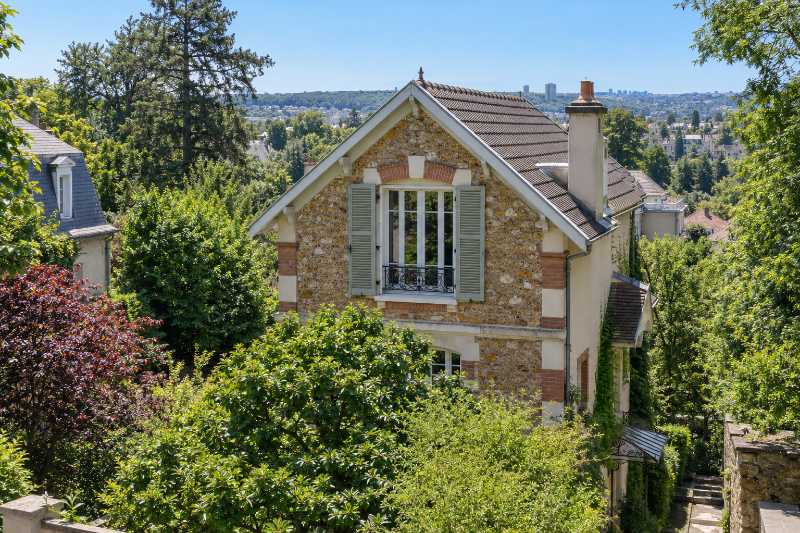 Fenêtre du dernier niveau d'une villa en meulière, vue depuis la rue située au-dessus