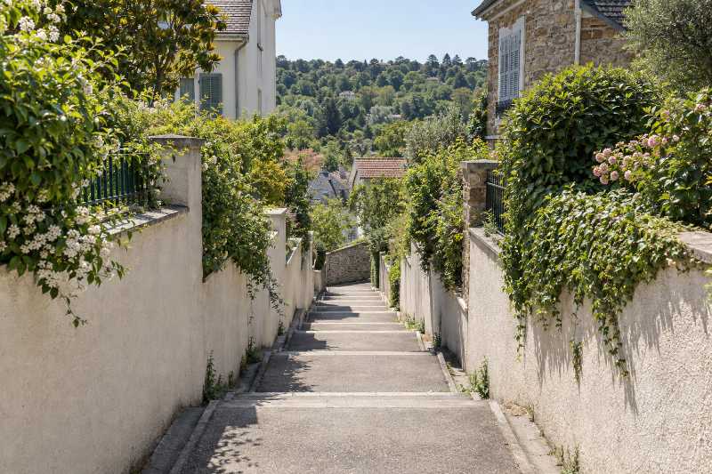 Sente piétonne à marches descendant entre deux murs vers la rue du bas